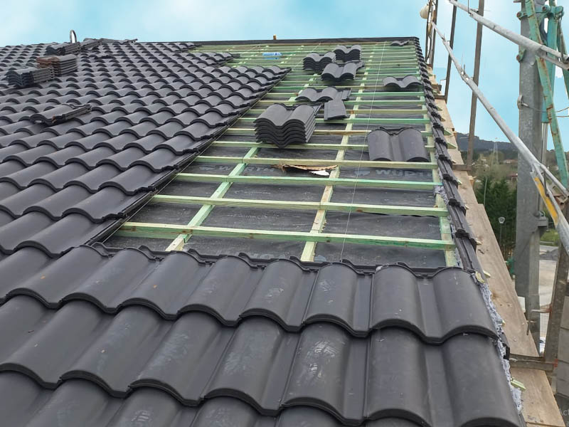 tejado de tejas oscuras en proceso de instalación con andamio al lateral